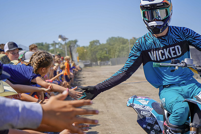 an ATV racer gives high fives to children in the crowd