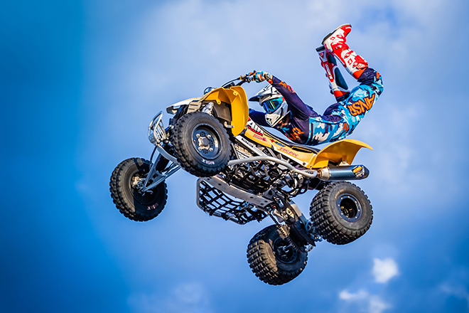a rider doing a Superman trick in middair on an ATV