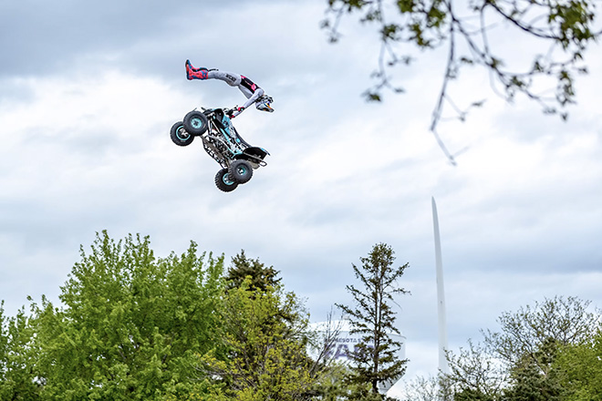 an ATV rider does a trick jump above the treetops