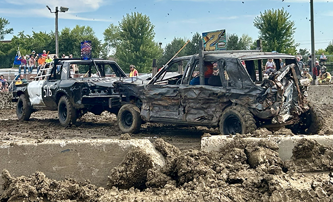 two smashed up cars kick up mud at the Carver County Fair Demolition Derby