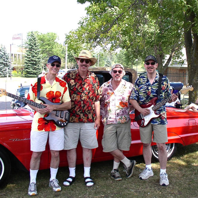The Castaways band poses with a red vintage sports car