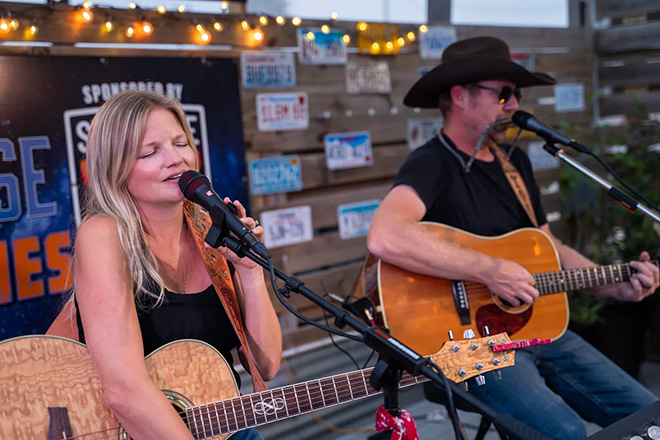 Leavin Page Town band - a woman sings while a man plays a harmonica and strums an acoustic guitar