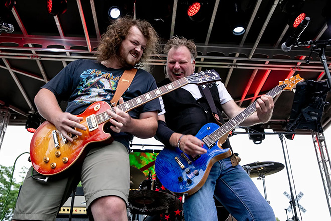 two guitar players from Muddcat Melby playing on stage