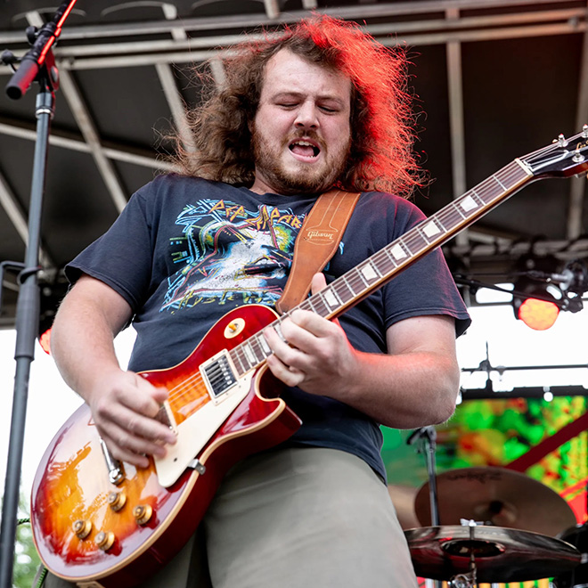 a guitar player from Muddcat Melby makes a face for the camera