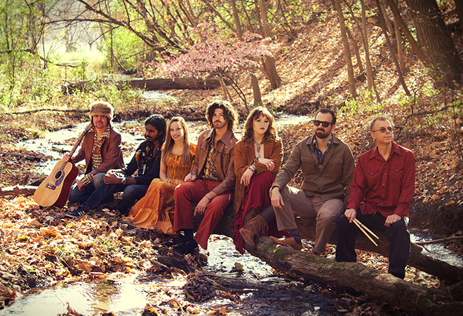members of the band Sawyers Dream sitting on a log over a creek
